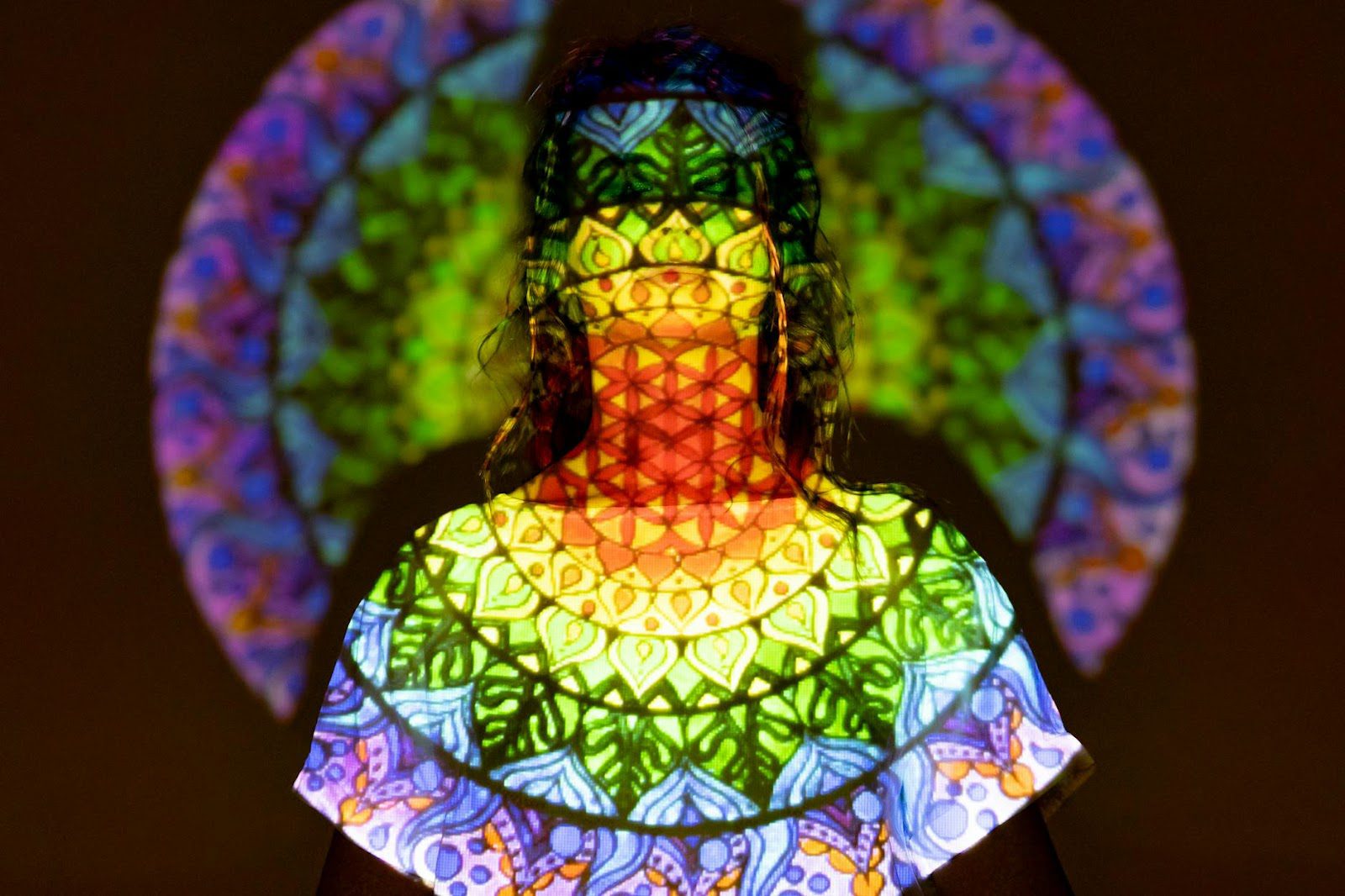 Colorful mandala patterns projected onto silhouette, creating a serene atmosphere.